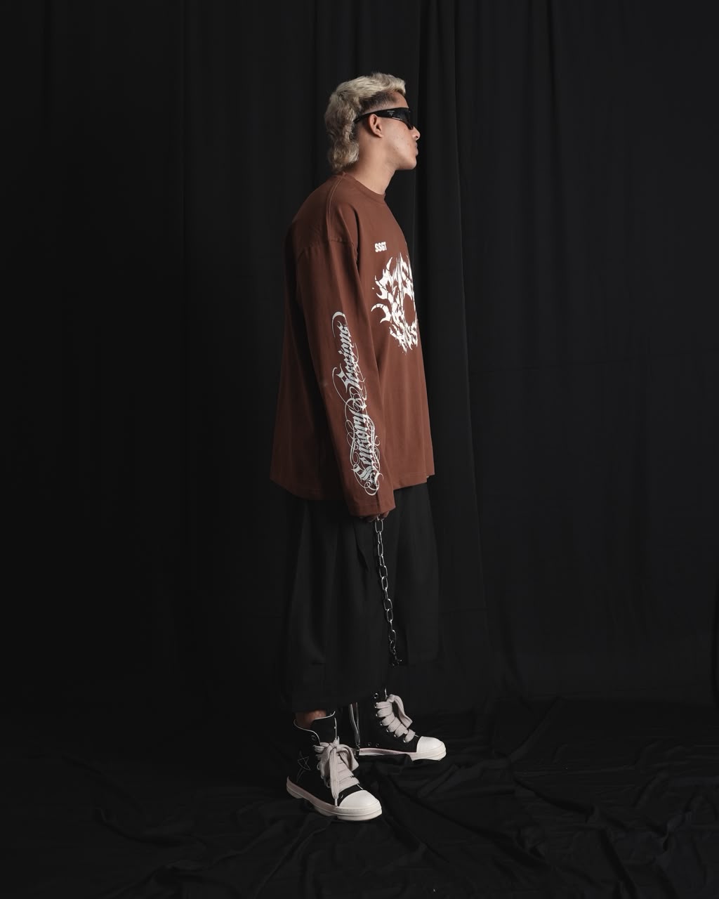 BROWN oversized full-sleeve graphic T-shirt with distressed white front print and sleeve designs on a male model.