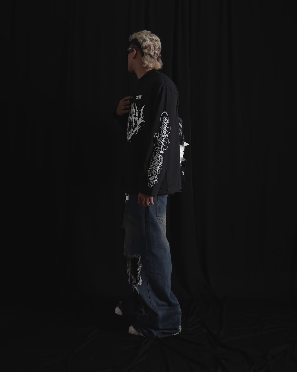 black oversized full-sleeve graphic T-shirt with distressed white front print and sleeve designs on a male model.