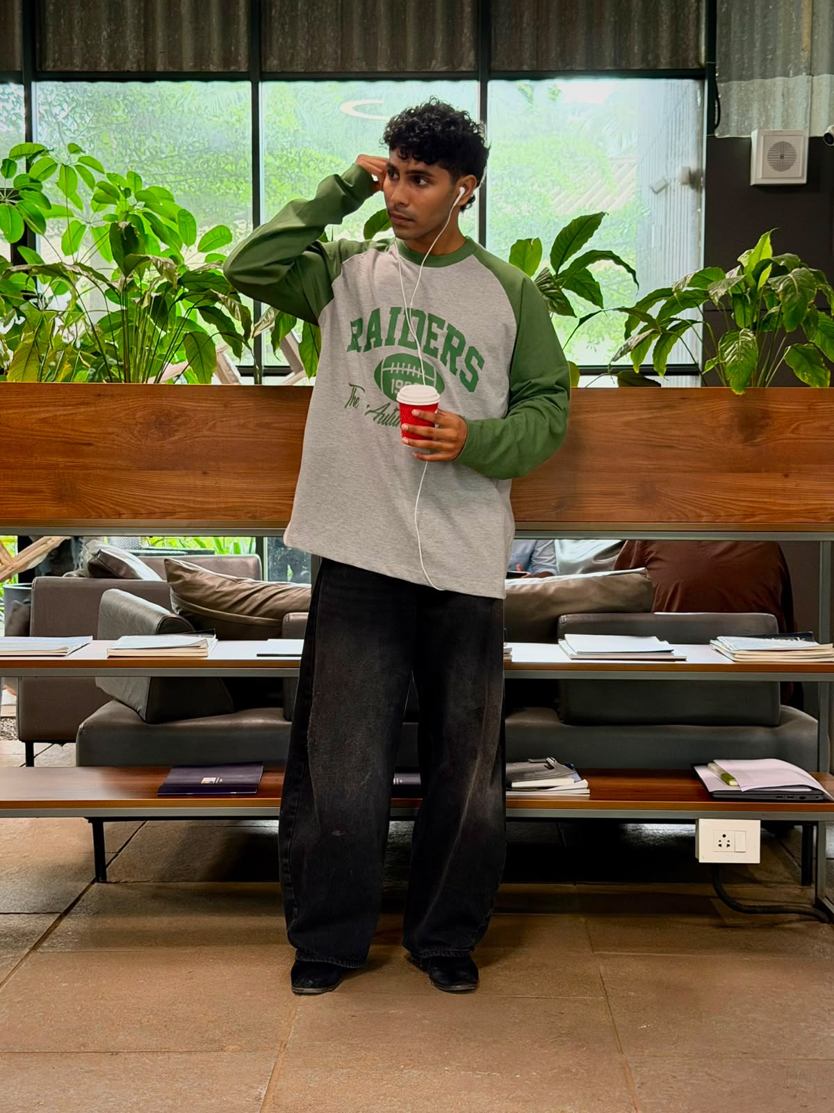 Model wearing a vintage oversized grey and green Raiders raglan full sleeve graphic T-shirt