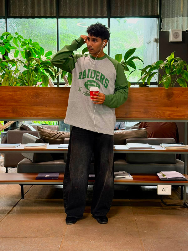 Model wearing a vintage oversized grey and green Raiders raglan full sleeve graphic T-shirt