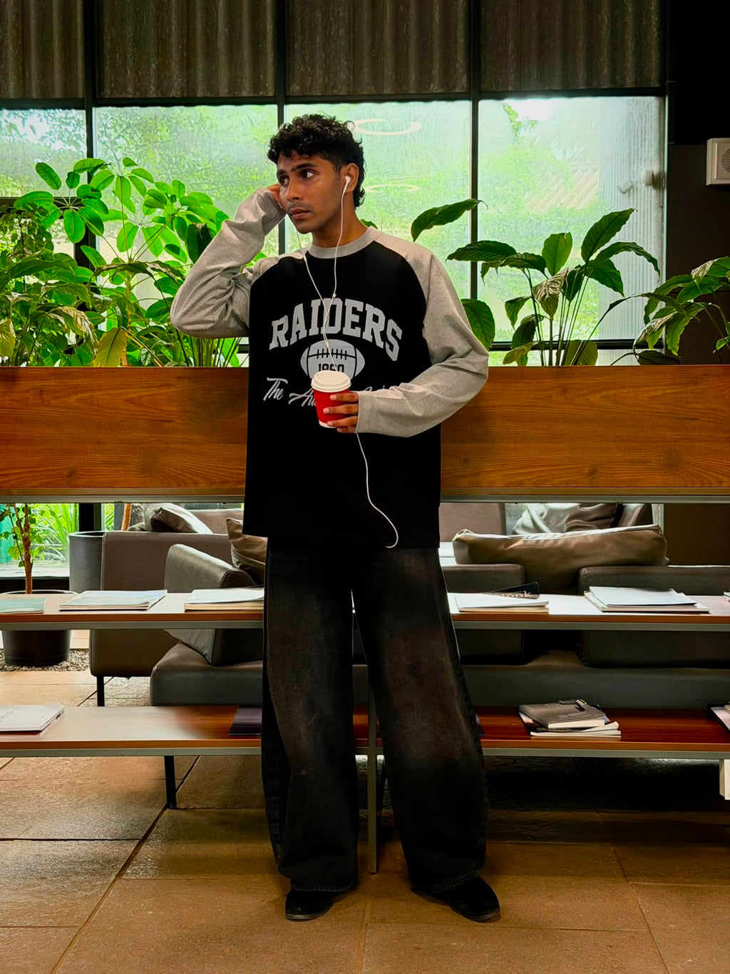 Model wearing a vintage oversized grey and black  Raiders raglan full sleeve graphic T-shirt