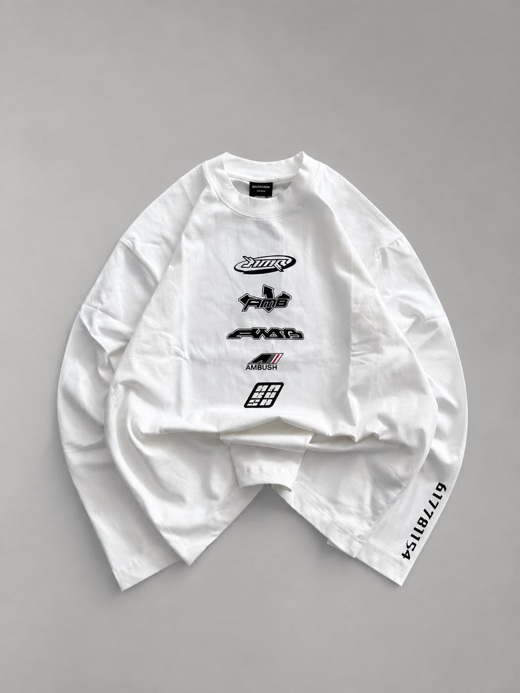 White oversized long sleeve graphic T-shirt featuring a distressed red cross circle front print and bold red sleeve graphic, laid flat on a white background for streetwear fashion.