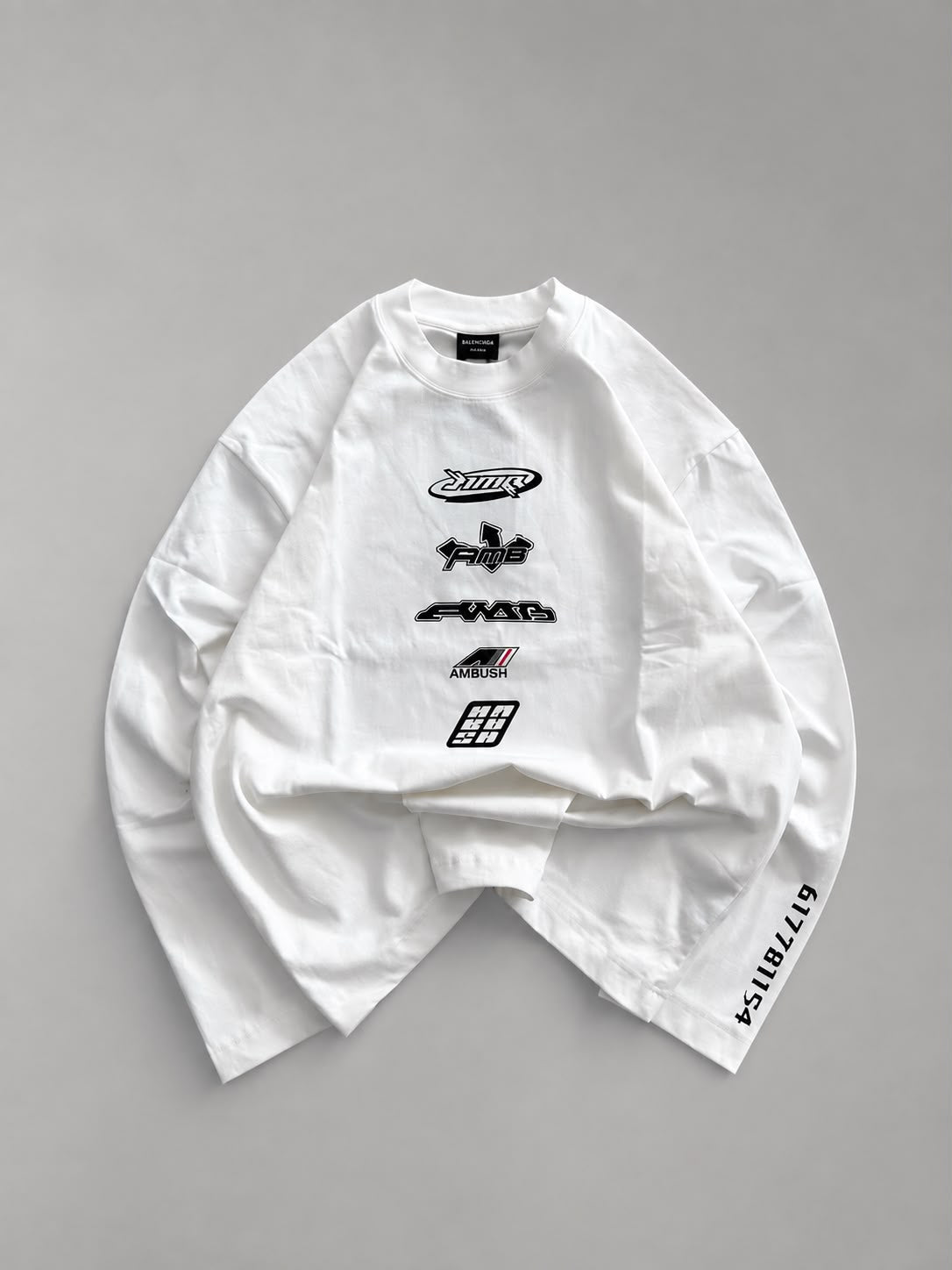 White oversized long sleeve graphic T-shirt featuring a distressed red cross circle front print and bold red sleeve graphic, laid flat on a white background for streetwear fashion.