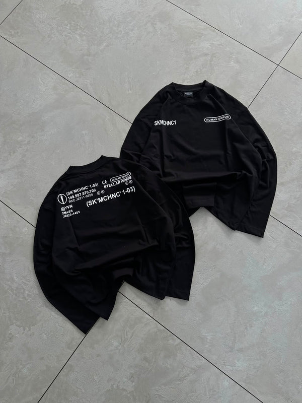 Black full-sleeve graphic T-shirt styled with baggy shorts for a modern streetwear look.