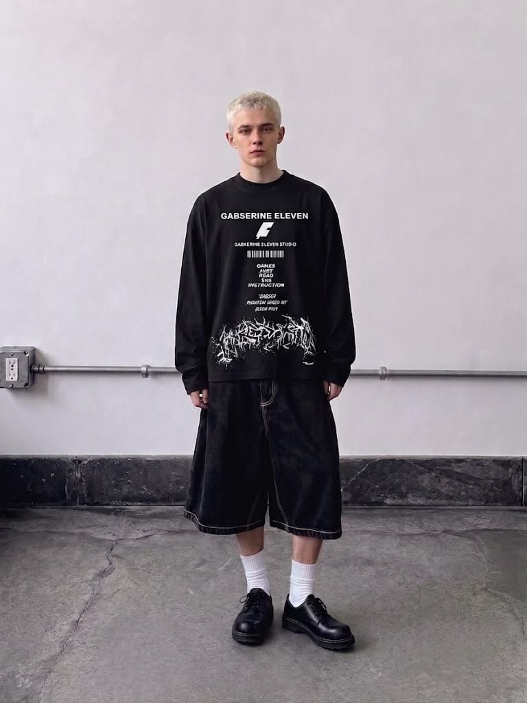 Black full-sleeve graphic T-shirt styled with baggy shorts for a modern streetwear look.